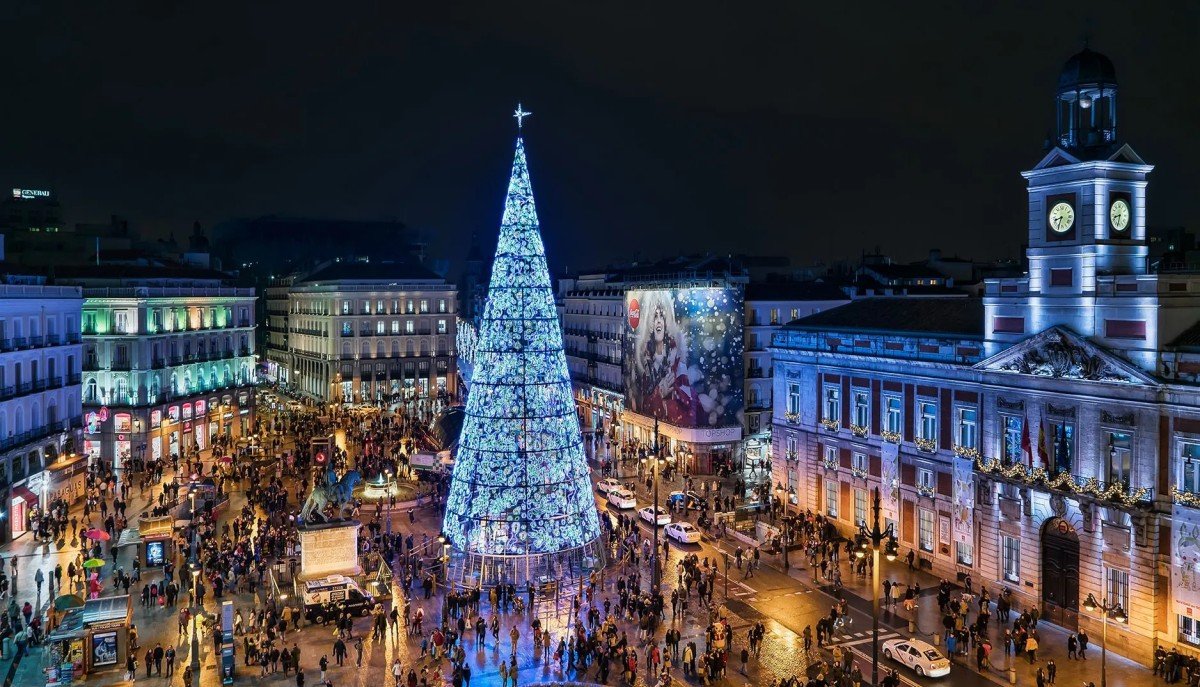 Large Christmas light installations and crowds in a main square of Madrid, lightning up surrounding ornate buildings